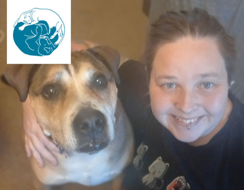 A woman is posing with a dog in front of a blue logo.
