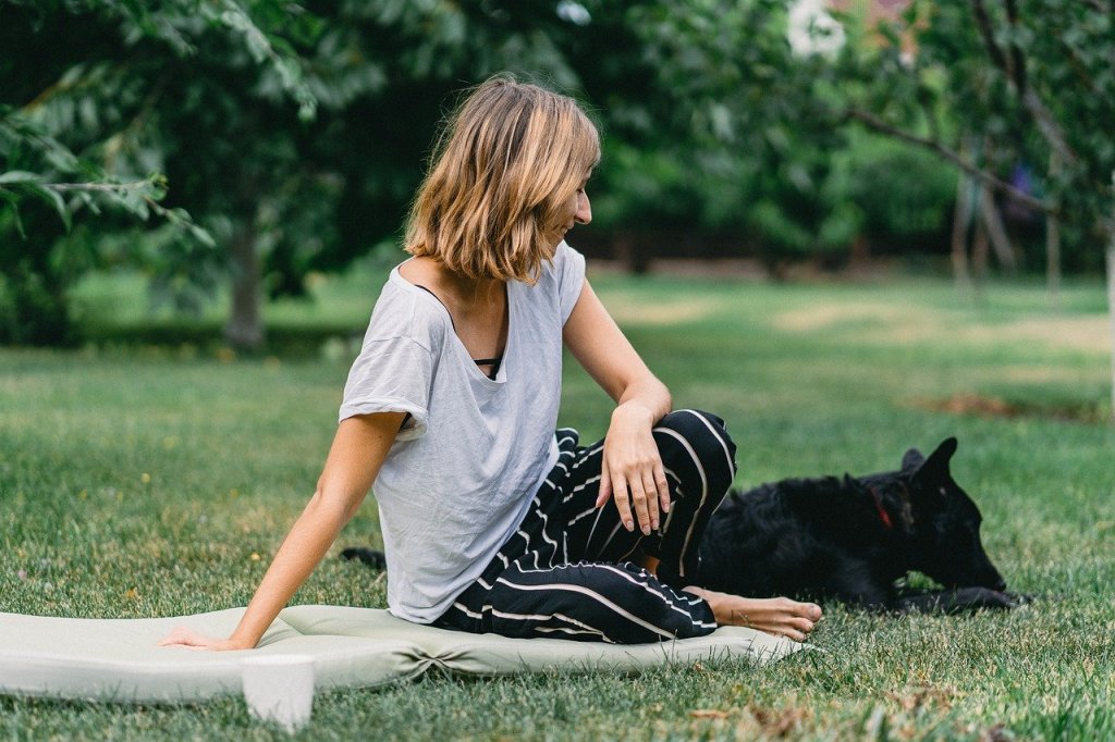 A woman practices yoga with her dog during Lesson 1 of Month 1.