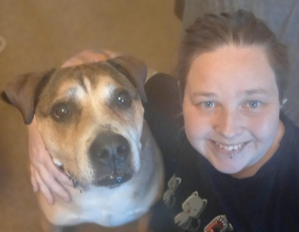 A woman smiling with her dog, showcasing the team dynamic in the living room.