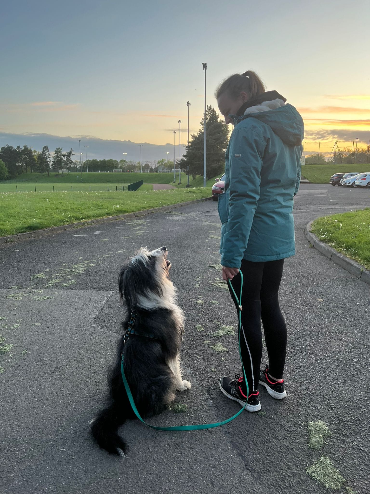 A woman is standing next to a dog on a leash while booking her rehabilitation.